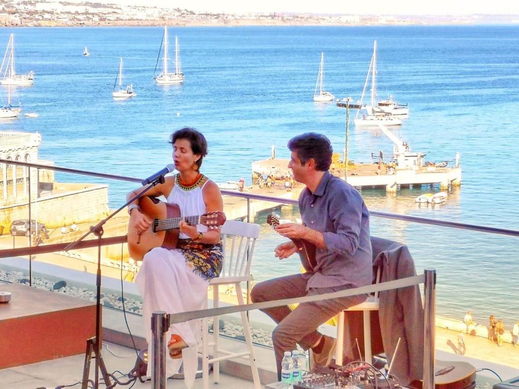 a man and a woman sitting on a balcony playing guitar at Hotel Baia in Cascais