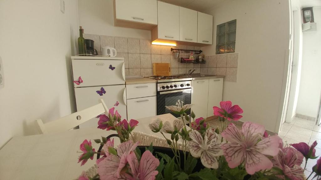 a kitchen with a white refrigerator and pink flowers at Apartman Goga in Draga Bašćanska