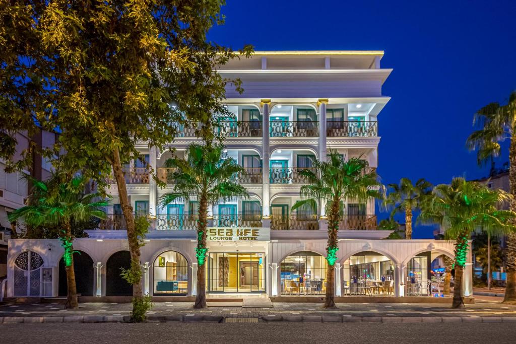 un grand bâtiment blanc avec des palmiers devant lui dans l'établissement Sealife Lounge - Adult only, à Antalya