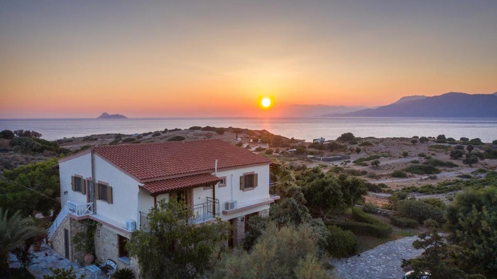 ein Haus auf einem Hügel mit Sonnenuntergang im Hintergrund in der Unterkunft Irene Komos in Pitsidia