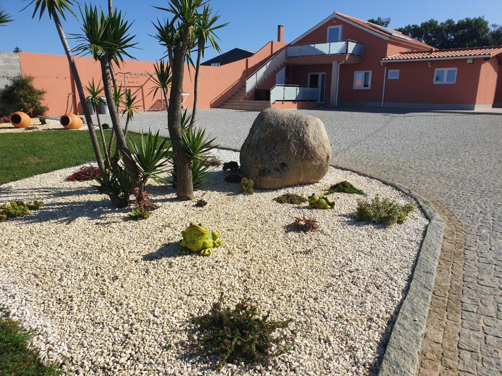 a garden with a rock and palm trees and a house at Hollidays Dreams in Póvoa de Varzim