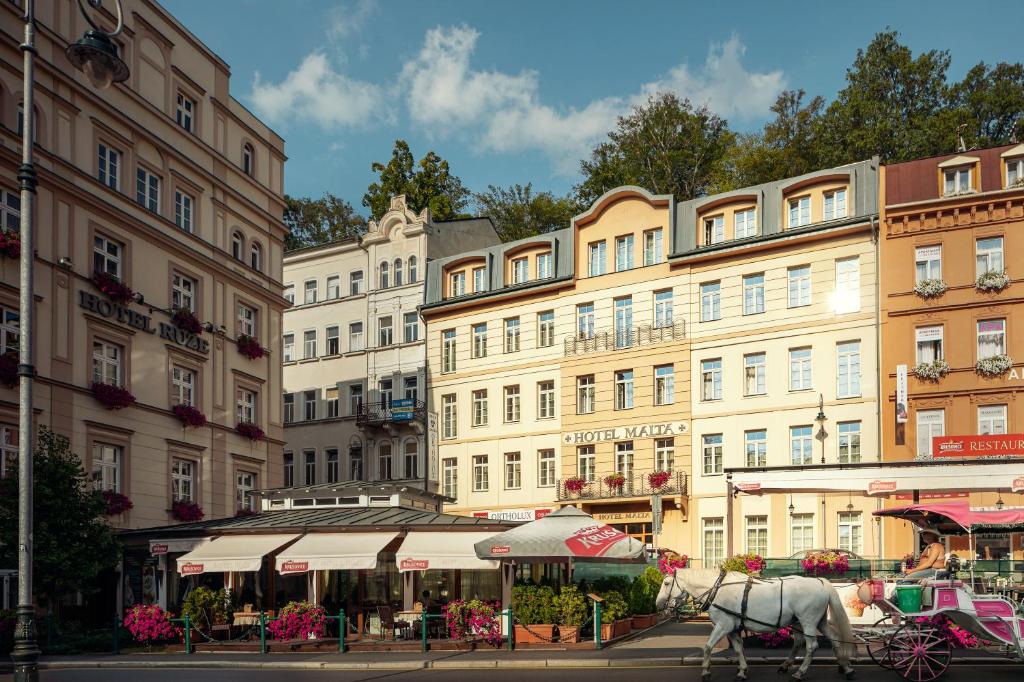 a horse drawn carriage in front of a building at Hotel Malta in Karlovy Vary