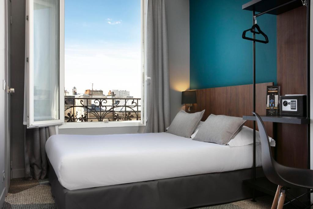 łóżko w pokoju z dużym oknem w obiekcie Montparnasse Alésia w Paryżu