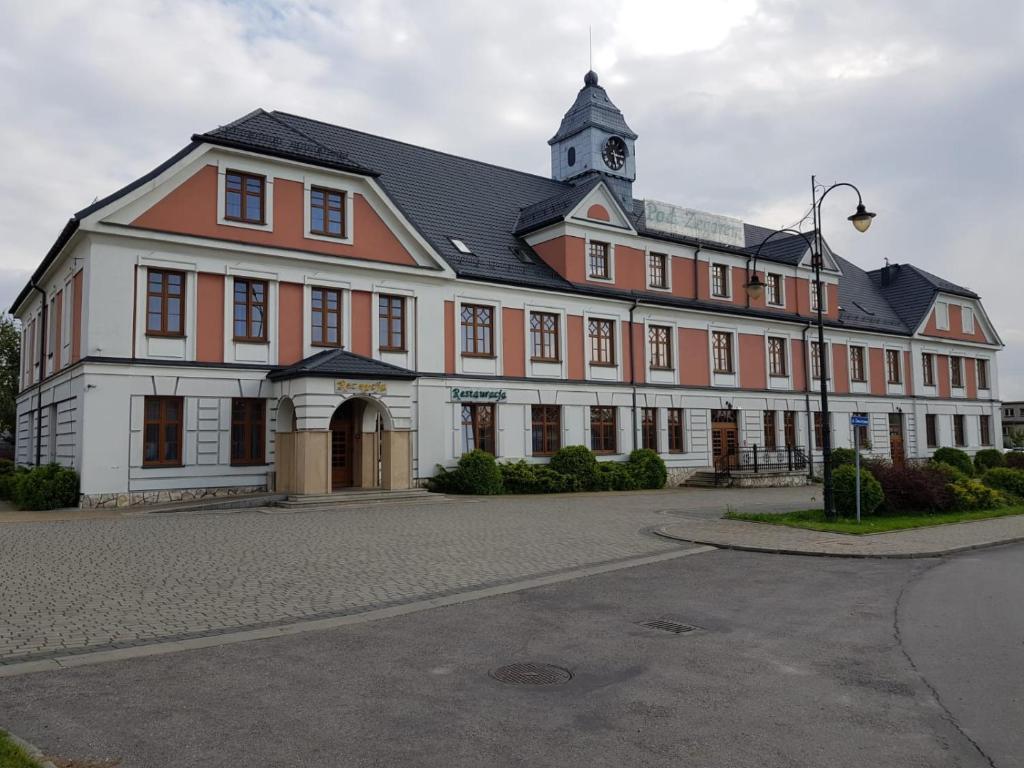 a large orange and white building with a clock tower at Rezydencja Pod Zegarem in Trzebinia