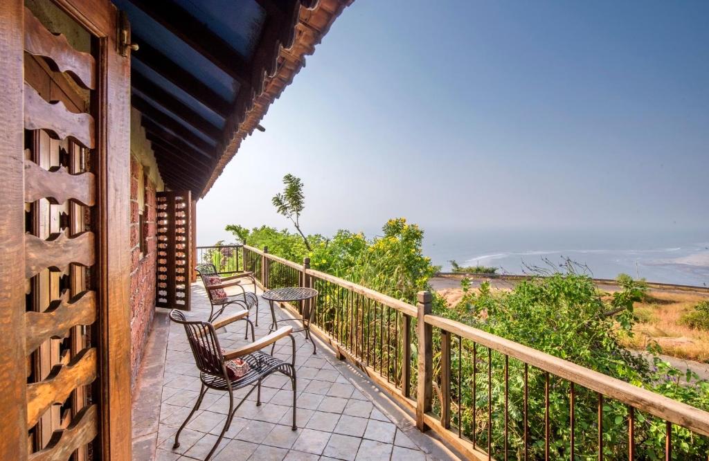 a porch with chairs and a table on a balcony at SaffronStays Villa 270, Dapoli in Dapoli