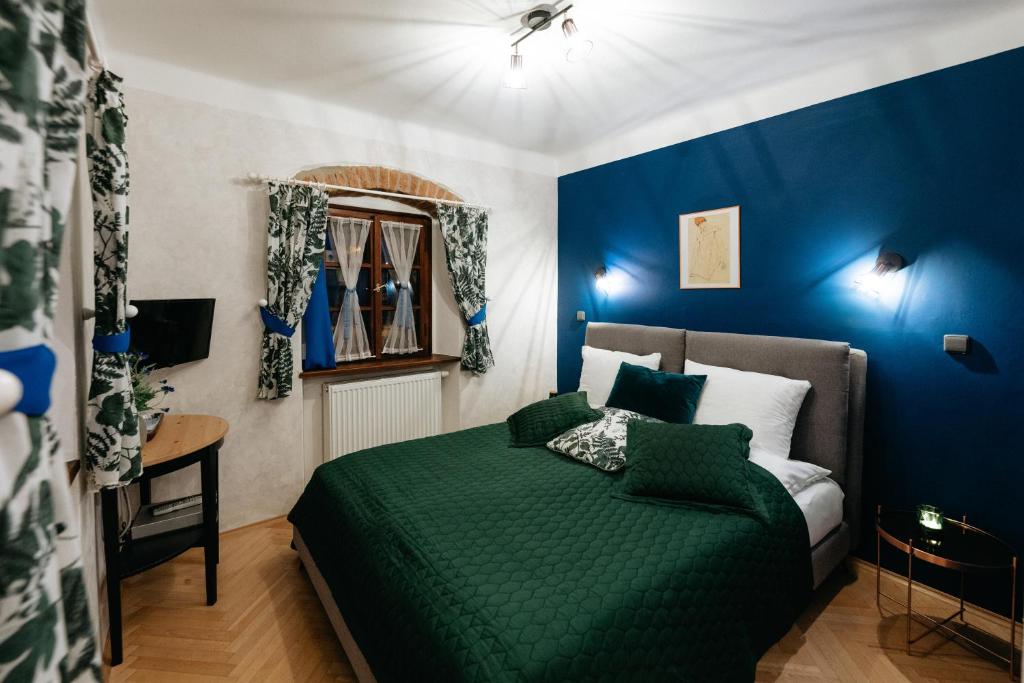 1 dormitorio con cama verde y pared azul en Boutique Hotel Romantick en Český Krumlov