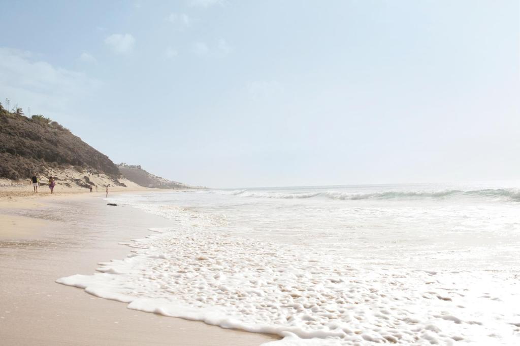 a beach with the waves coming in from the ocean at ROBINSON ESQUINZO PLAYA - All Inclusive in Morro del Jable