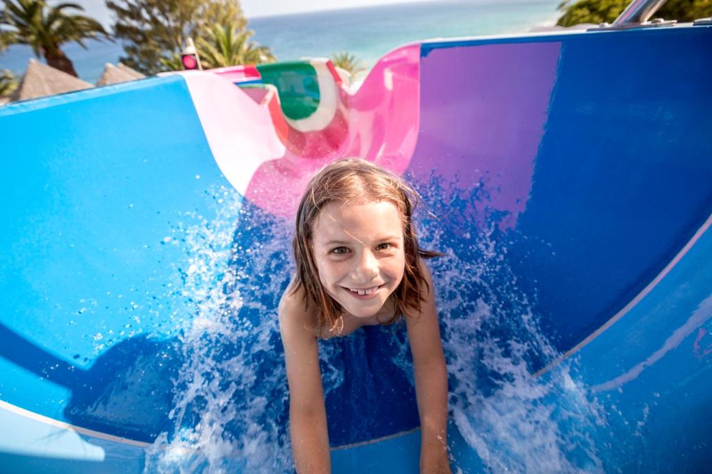 a little girl riding on a water slide at ROBINSON ESQUINZO PLAYA - All Inclusive in Morro del Jable
