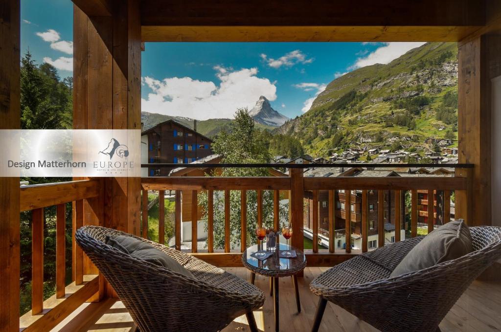 a balcony with two chairs and a table and mountains at Europe Hotel & Spa in Zermatt