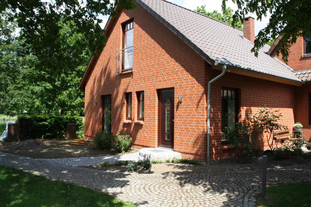 uma casa de tijolos vermelhos com um caminho à sua frente em Ferienwohnung Rehblick em Langwedel