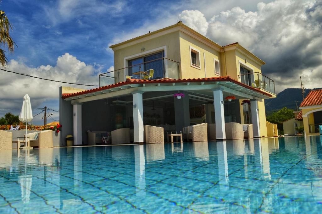 una casa con piscina di fronte a una casa di SunRose Beach Aparthotel ad Acharavi