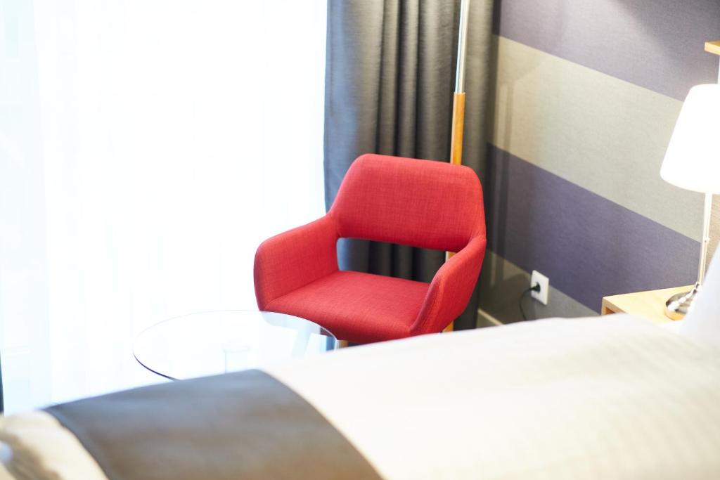 a red chair sitting next to a bed in a room at Hotel Garni am Schloss in Kottenheim