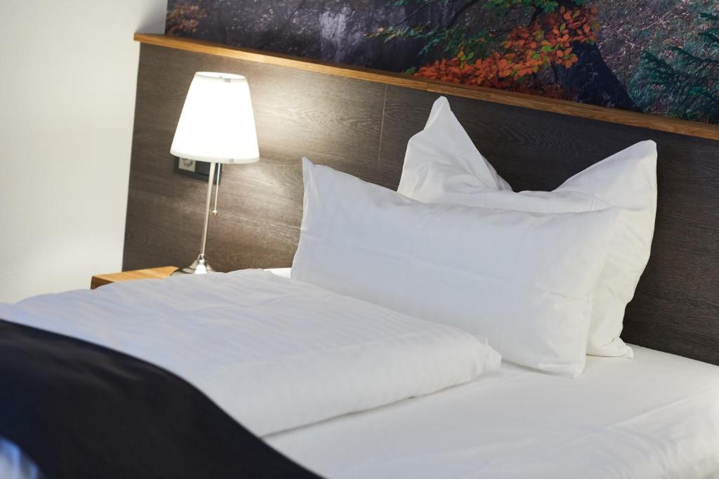 a white bed with white pillows and a lamp at Hotel Garni am Schloss in Kottenheim