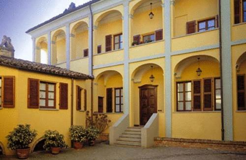 un grand bâtiment jaune avec des escaliers et une porte dans l'établissement Locanda Martelletti, à Cocconato