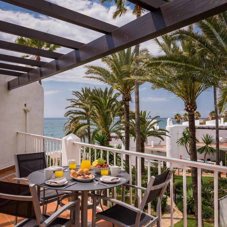 a table and chairs on a balcony with the ocean at Macdonald Leila Playa Resort in La Cala de Mijas