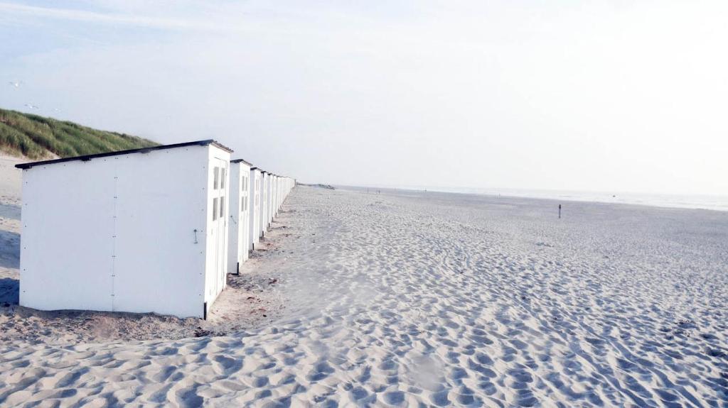 - un bâtiment blanc sur une plage de sable près de l'océan dans l'établissement Carpe diem Noguchi 201- Adults Only, à Saint-Idesbald