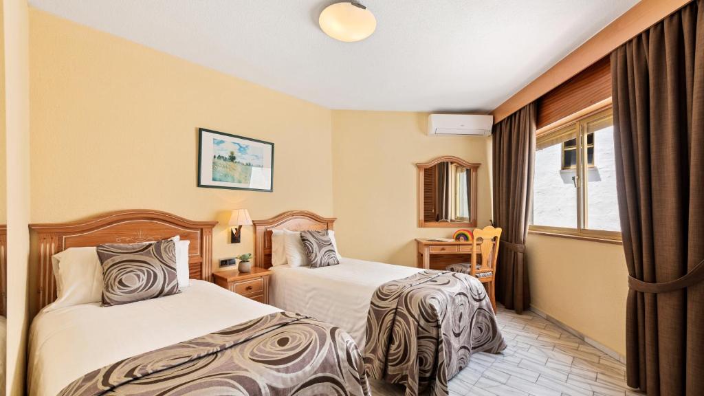 a hotel room with two beds and a window at Macdonald Leila Playa Resort in La Cala de Mijas