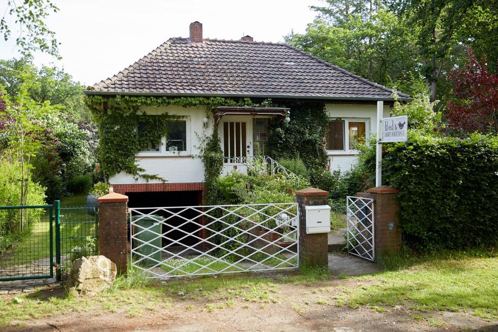 Uma casa branca com um portão à frente. em Bed & Breakfast Wesseloh em Schneverdingen