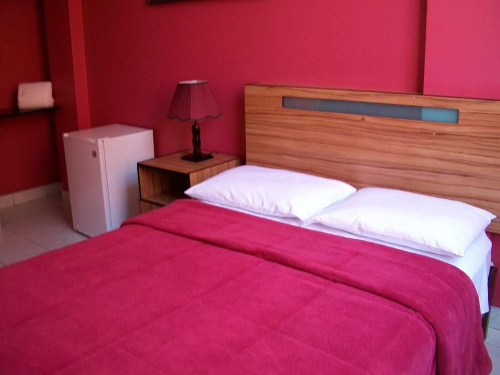 a bedroom with a large bed with a red wall at Hostal Hellen Ross in Nazca