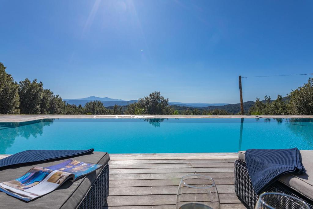 a large swimming pool with two chairs and a table at Villa Casenovole in Murlo