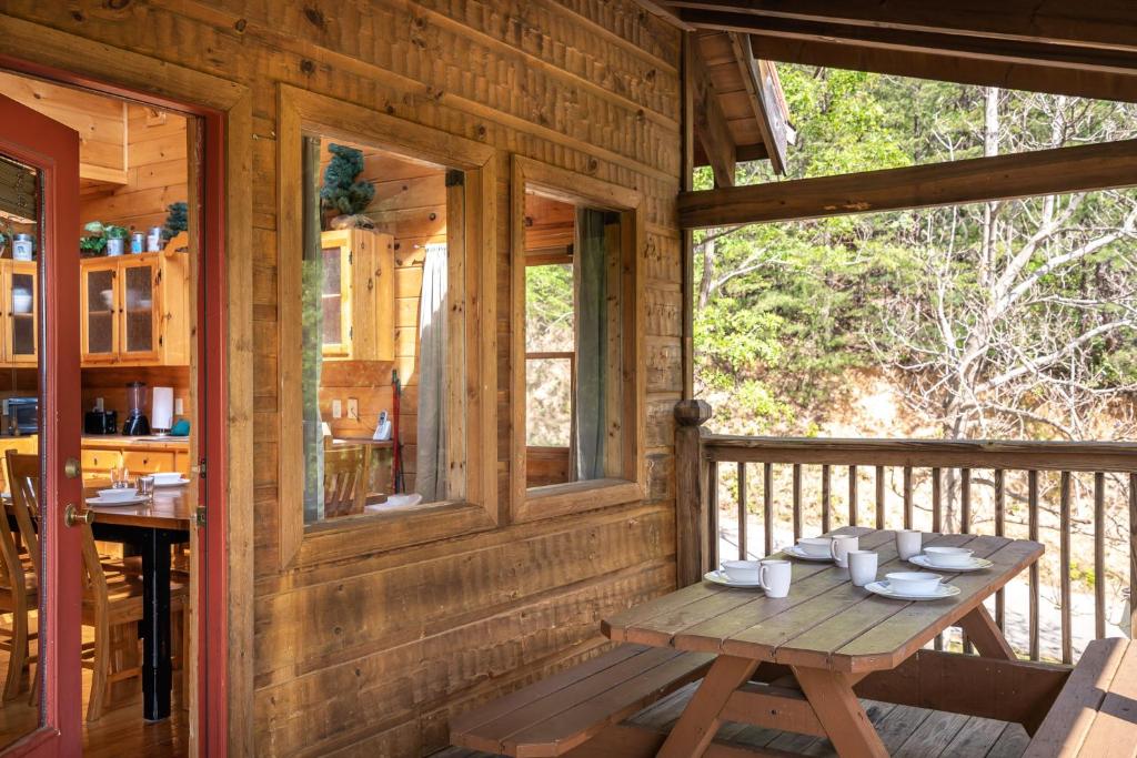 a wooden porch with a wooden table on a deck at Mountain Tyme, Hot Tub, Pool Table, Game Room, 560 FREE tickets each paid day! in Sevierville