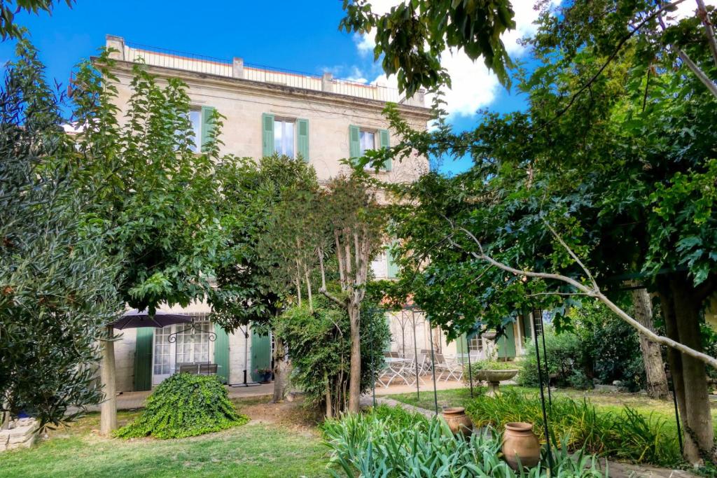 an old house with trees in front of it at Au Saint Roch - Hôtel et Jardin in Avignon