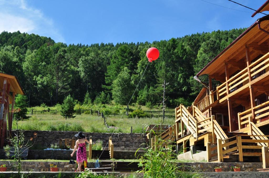 a girl flying a red balloon in front of a building at Bajkalskie Prostory in Listvyanka
