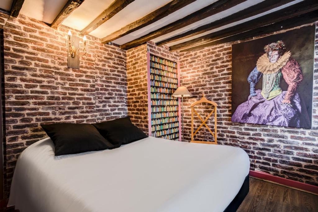 una camera con un letto bianco su un muro di mattoni di Absolute Hotel Paris République a Parigi