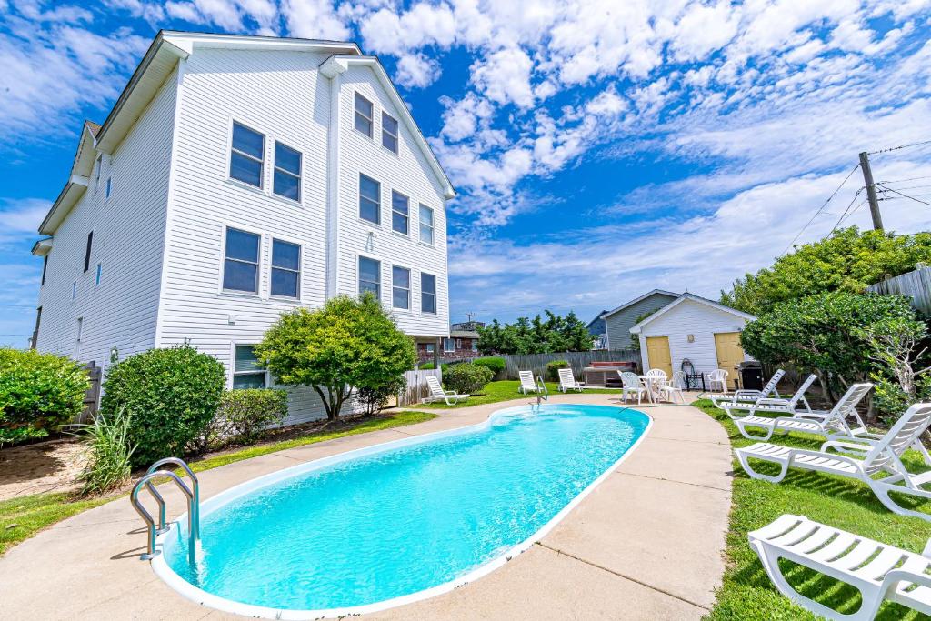 a swimming pool in front of a house at Sunny Delight - KDH MP 7, Ocean View, 130 Yds to Beach, Pool, Hot Tub, Pets OK, Flex Stays in Kill Devil Hills