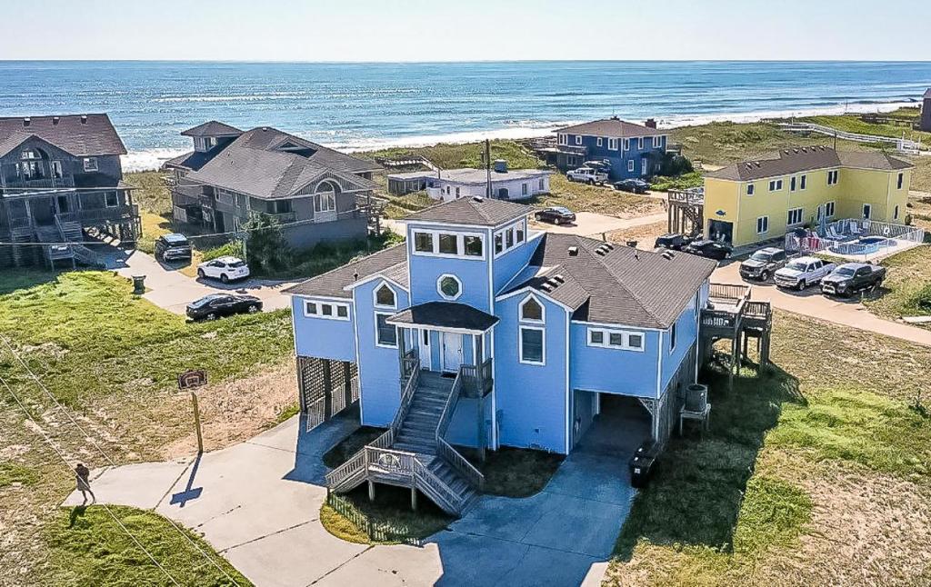 a blue house with a spiral staircase in front of the ocean at Swink Cottage in Southern Shores