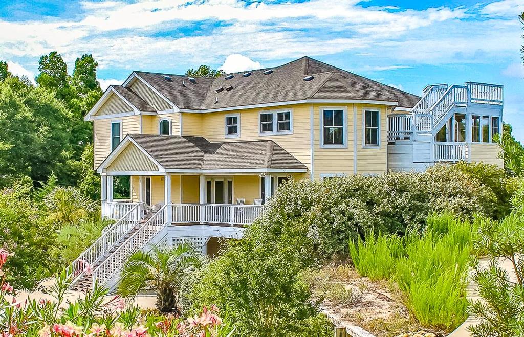 a large yellow house on a beach with bushes at Show Boat in Kitty Hawk