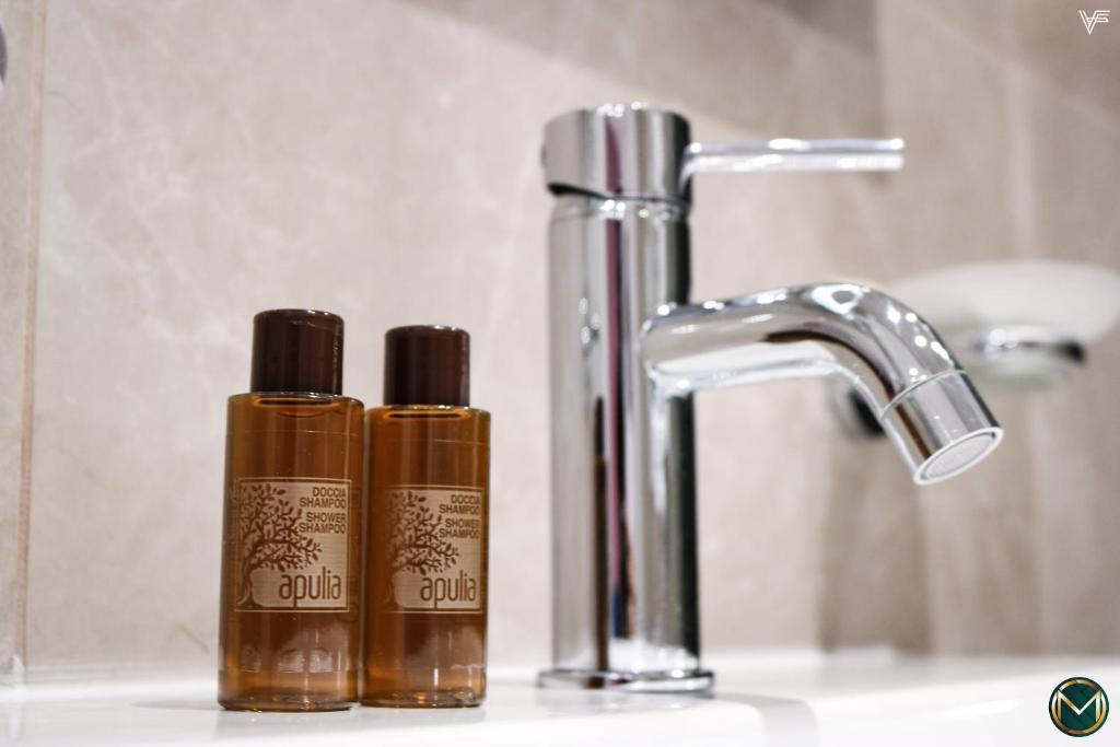 two bottles ofodorizers on a sink next to a faucet at MARGHERITA BOUTIQUE ROOMS in Margherita di Savoia
