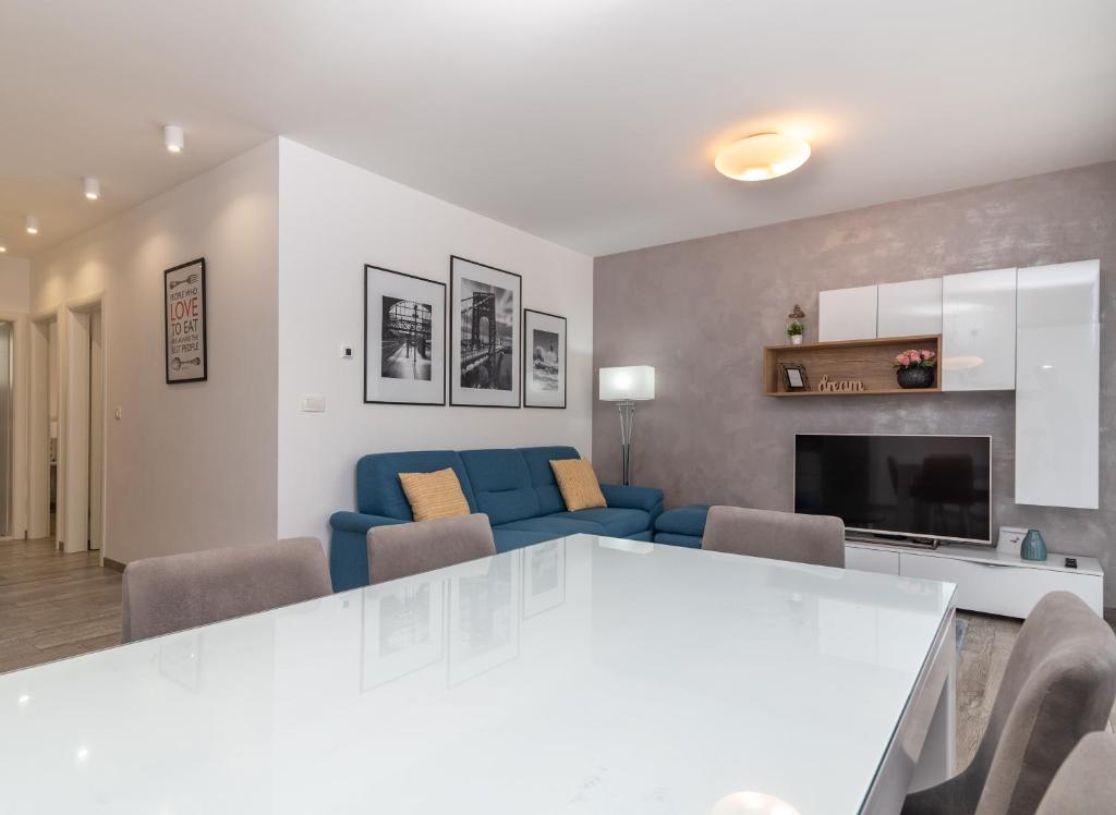un salon avec un canapé bleu et une télévision dans l'établissement Apartment Ferias, à Trogir