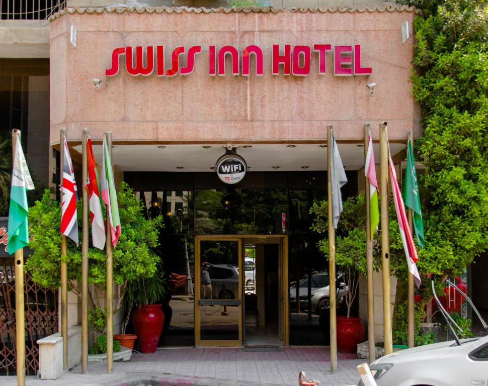 Swiss Inn Hotel Mohandeseen في القاهرة: فندق امامه مجموعه من الأعلام