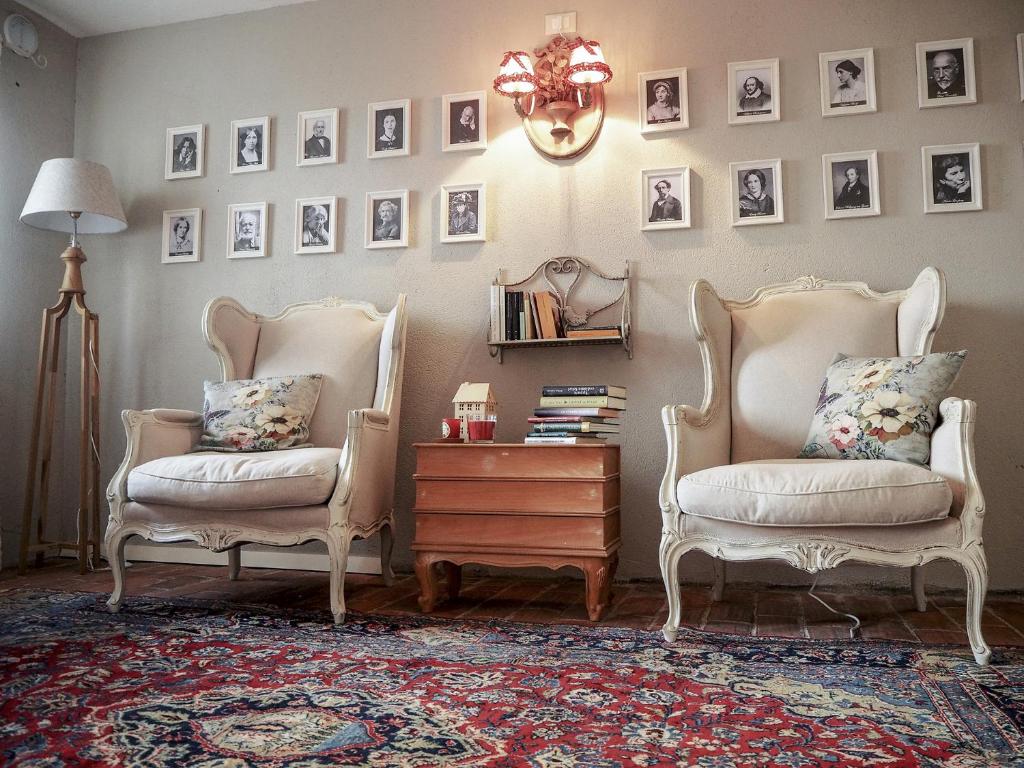 two chairs and a table in a room with pictures on the wall at B&B Antique Maison in Soave