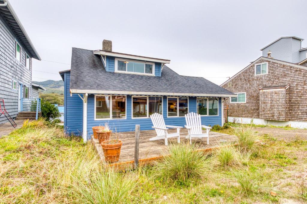 a blue house with two chairs on a deck at Our Happy Place in Rockaway Beach