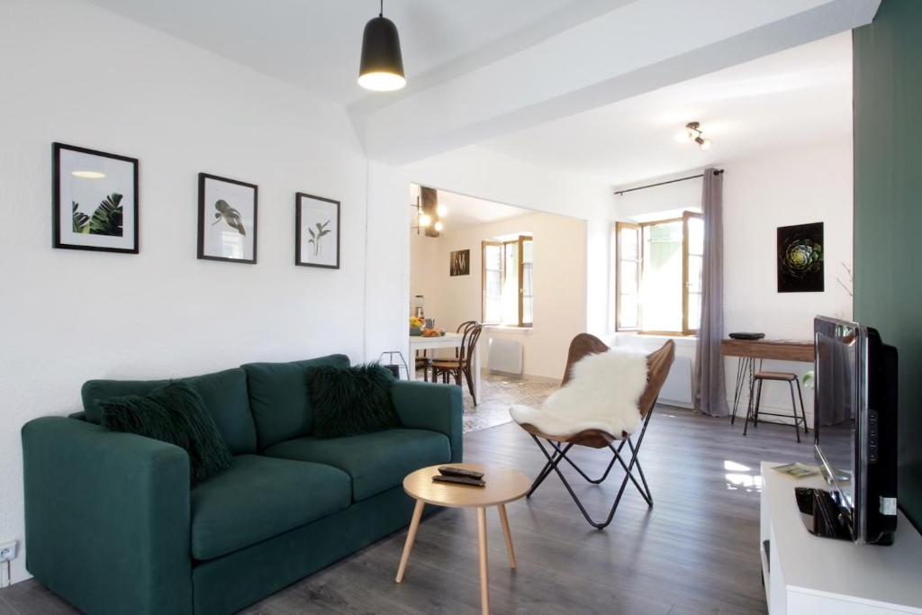 un salon avec un canapé vert et une table dans l'établissement Les Gîtes de Laure - L'Or Vert, Appartement avec Vue sur le Château, Parking Privé, Climatisation, Netflix, à 160 m de la Cité Médiévale, à Carcassonne