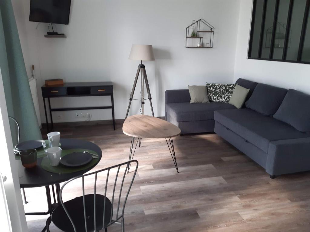 a living room with a blue couch and a table at COSYLOC studios in Cergy