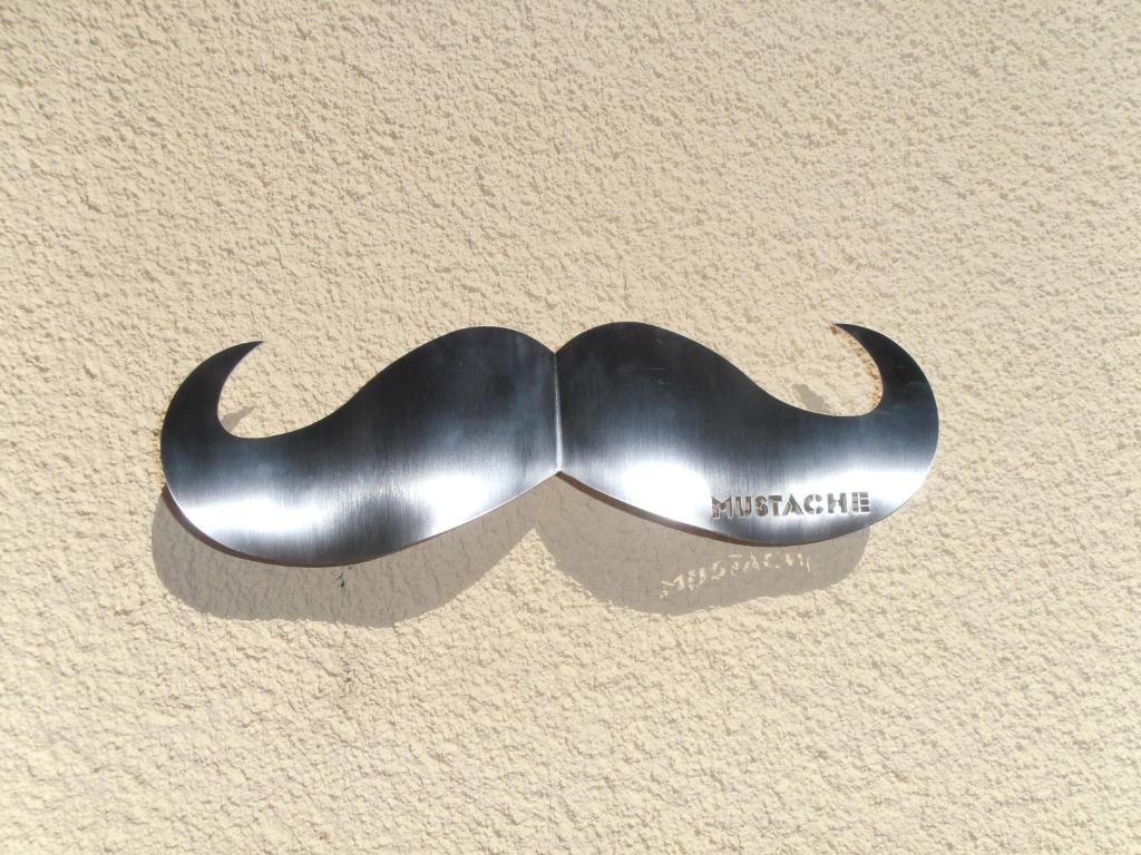 a metal moustache hanging on a wall at Mustache Studio in Ourém