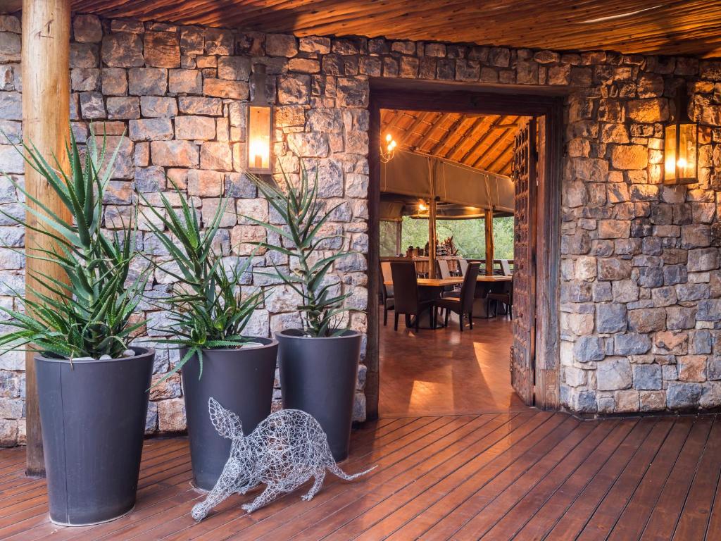 una habitación con macetas y una estatuilla de un perro en una cubierta en aha Thakadu River Camp, en Reserva de Madikwe