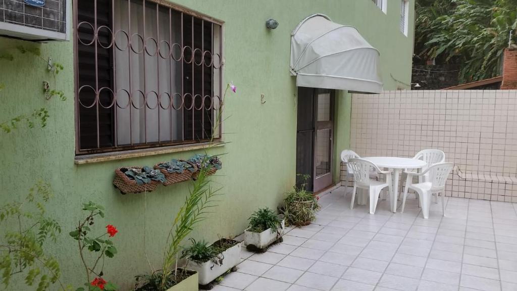 a patio with a white table and chairs on a house at Ubatuba Tenório apto térreo 6 pess in Ubatuba