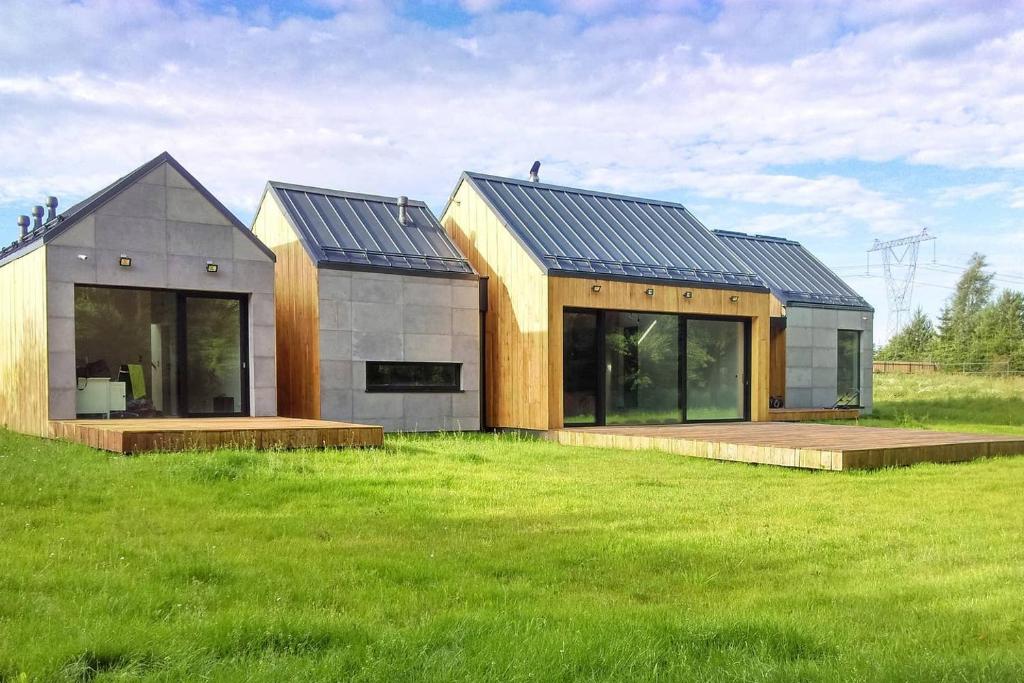 a house with a solar roof on a green field at Modern house in front of the forest in Słupsk