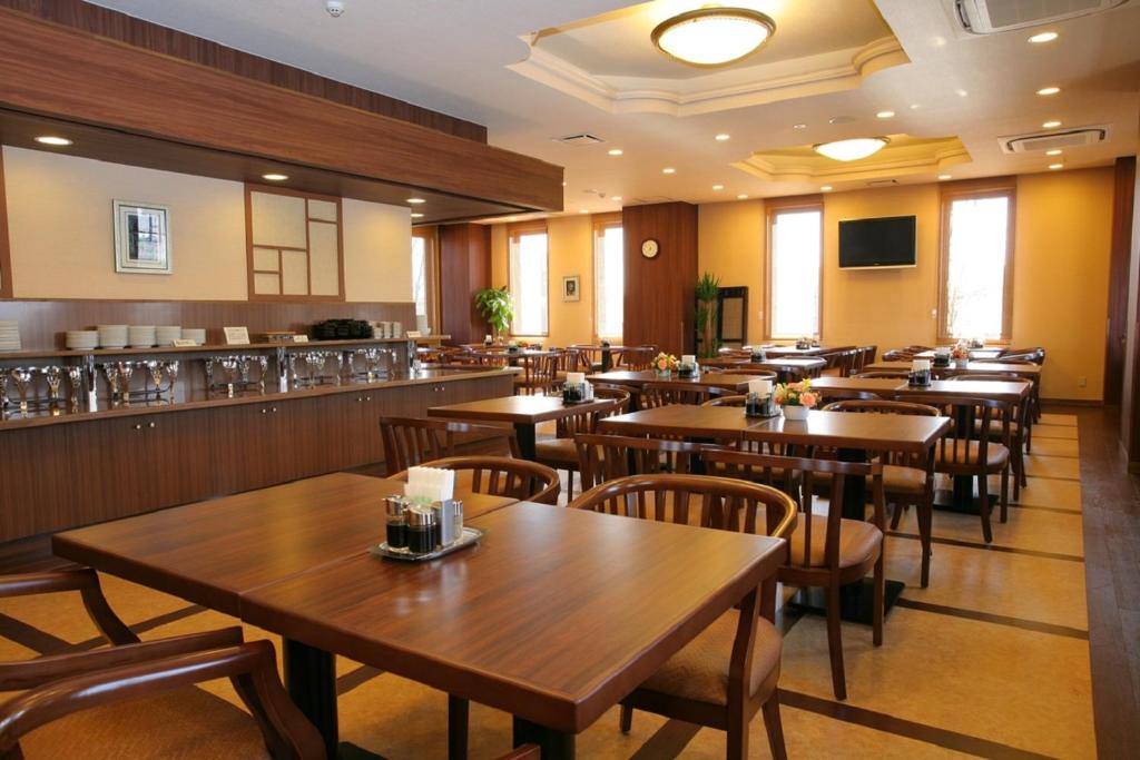 a restaurant with wooden tables and chairs and a bar at Hotel Route-inn Koriyama Inter in Koriyama