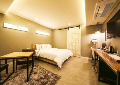 1 dormitorio con cama, mesa y escritorio en Jeonju Lime Hotel en Jeonju