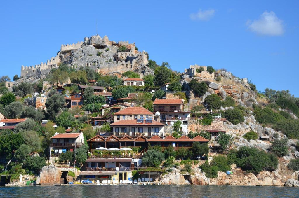 a village on a hill with houses on the water at Ankh Pension in Kaleucagız