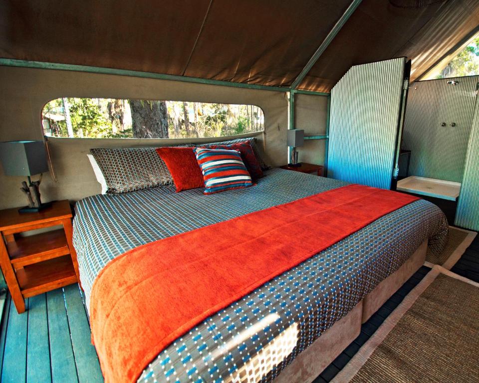 
a bed room with a bed and a bedside table at Mitchell Falls Wilderness Lodge in Camp Creek
