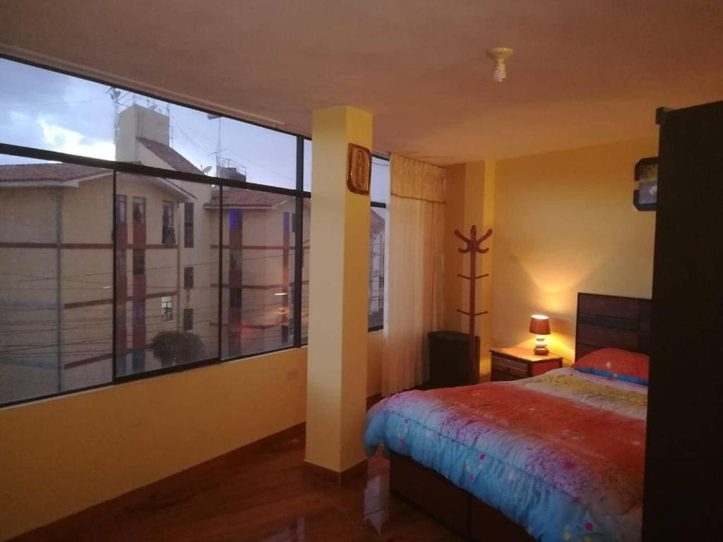 ein Schlafzimmer mit einem Bett und einem großen Fenster in der Unterkunft Apartamento amueblado, cómodo e independiente en Huancayo in Huancayo