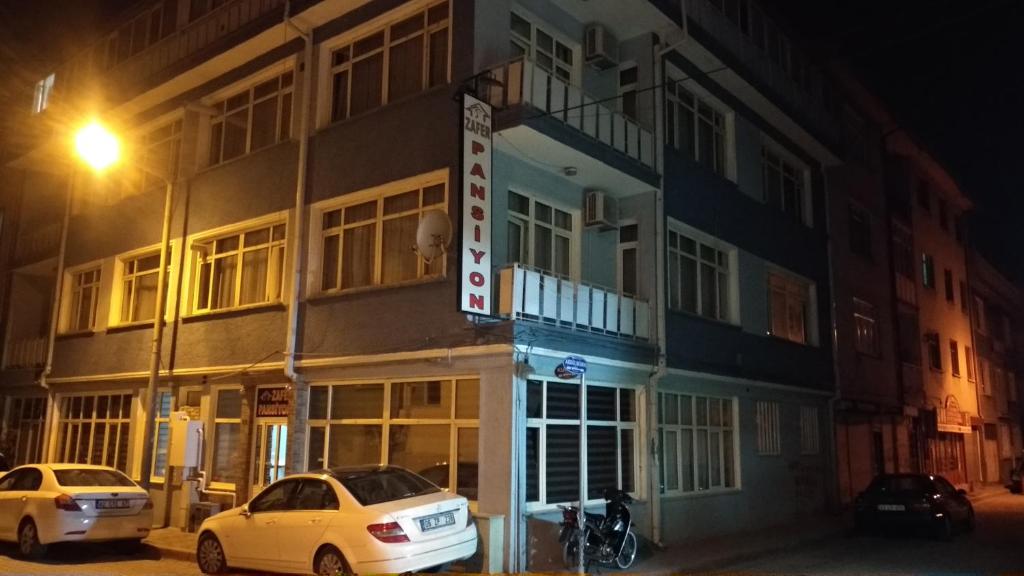 two cars parked in front of a building at night at Zafer Hostel in Konya