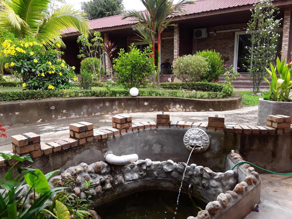 un jardín con una fuente de agua frente a una casa en Balai Serama Guesthouse, en Kuala Tahan