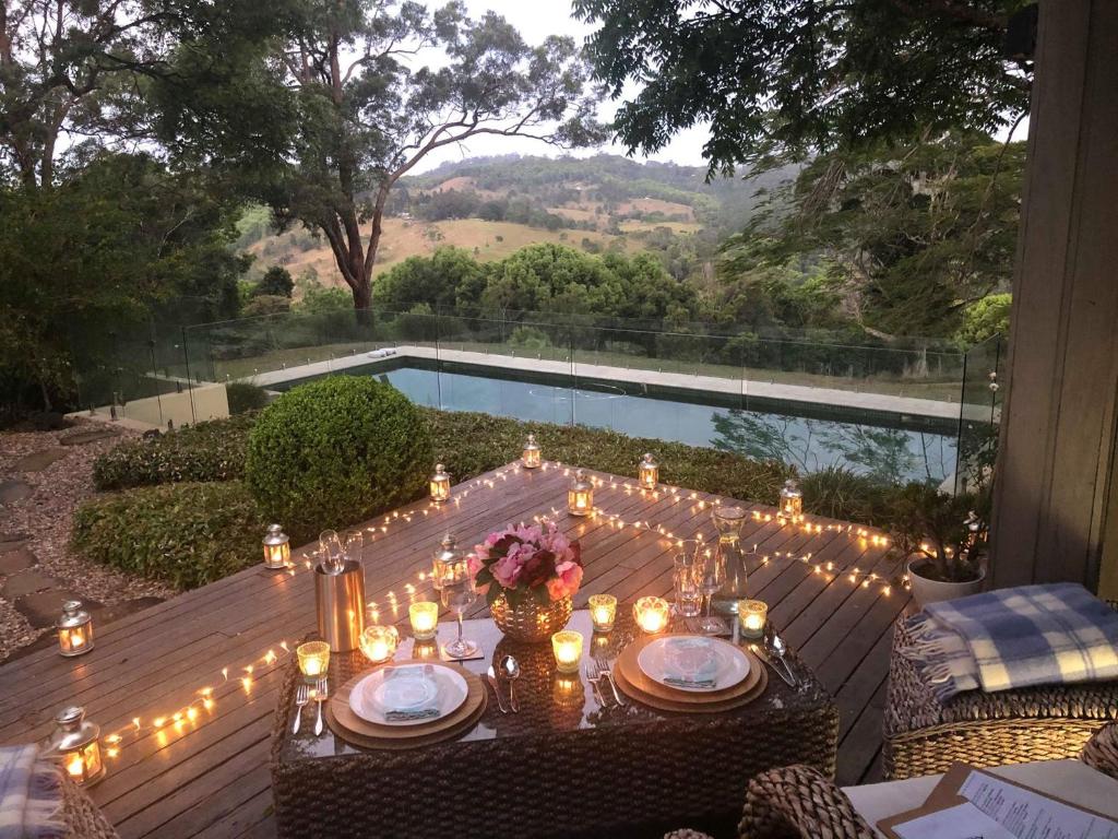 a table with candles and lights on a deck with a pool at Luxury Tee Pee Byron Bay in Minynon